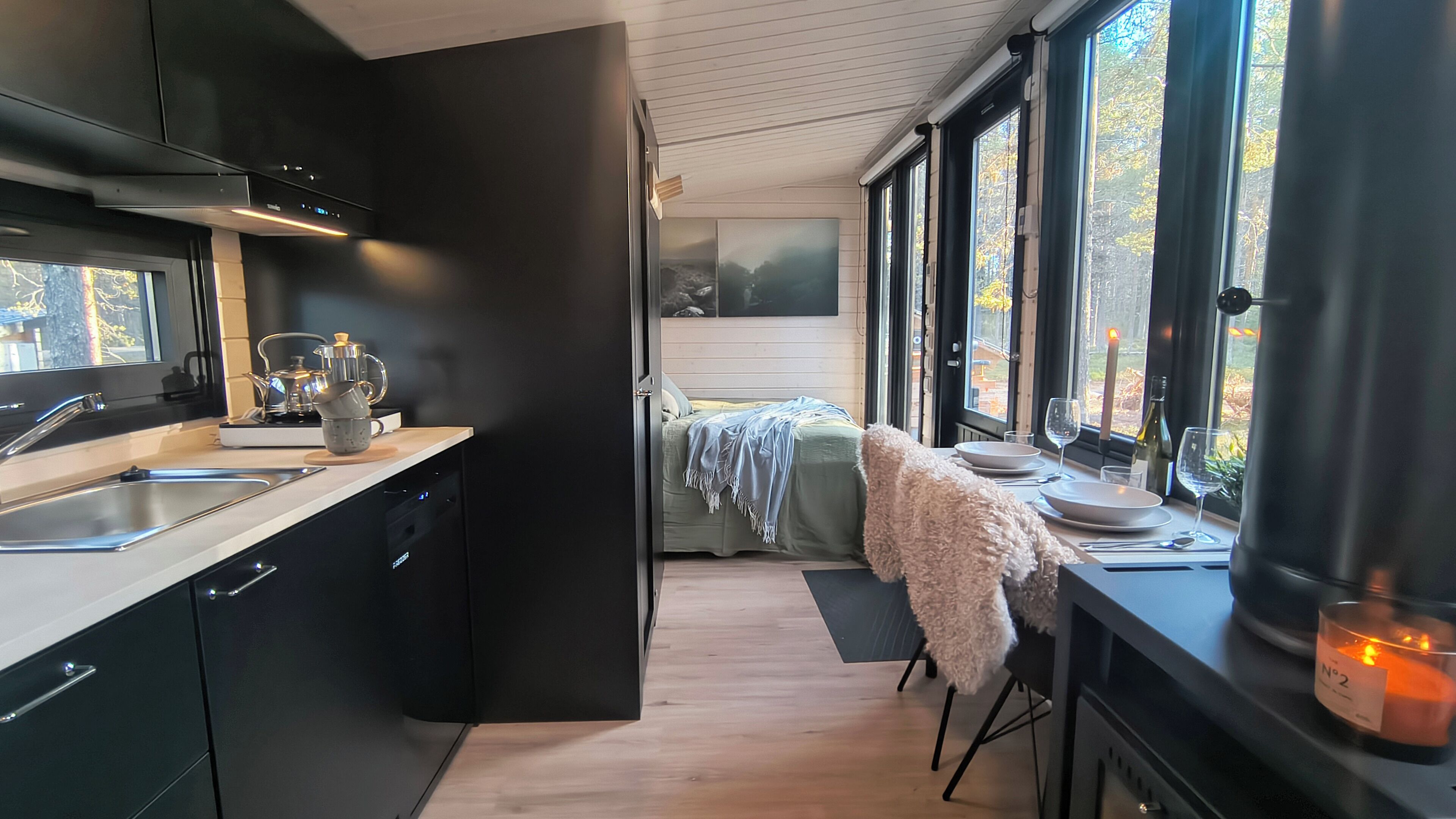 A modern kitchen with a sink, stove, and cabinets. A dining area with a table and chairs is visible through an open door.