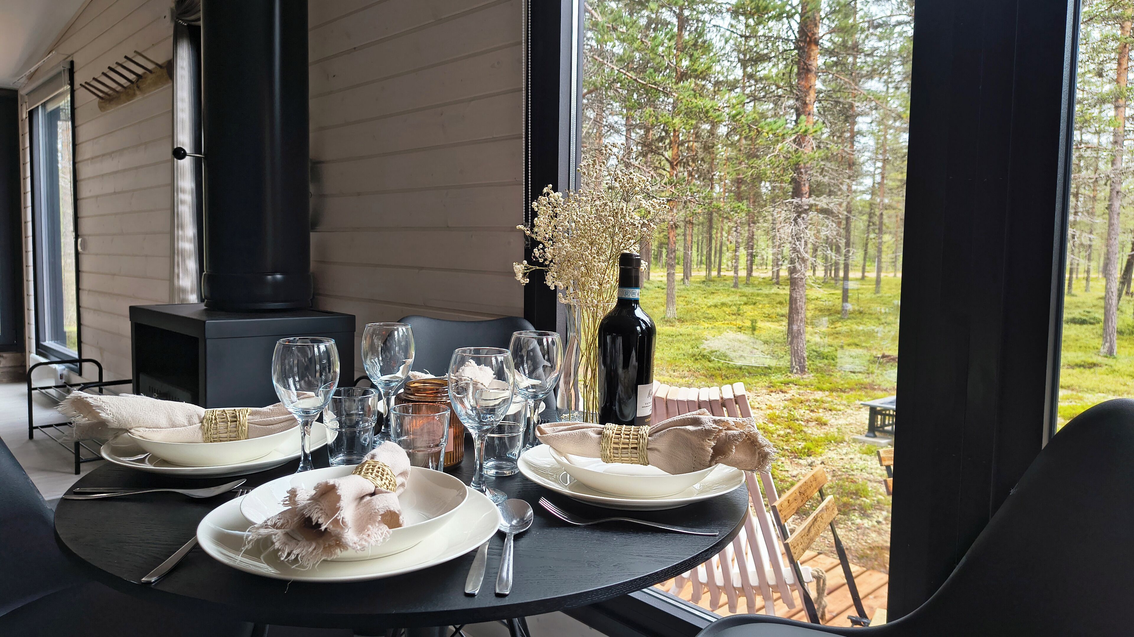 A dining table set outdoors with a view of a forest.