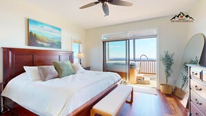A spacious bedroom with a large bed, a ceiling fan, a painting, a sliding glass door leading to a balcony with a hot tub, and a dresser with drawers. - Reserve 36C • Top of the World • Hot Tub (Sugar Mountain)