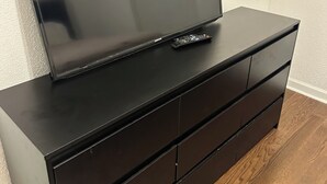 A black TV stand with a flat-screen TV and remote control. - 3-bedroom house in charming Southhull neighborhood, close to downtown! (Montgomery)