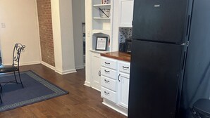 A kitchen with wooden flooring, white cabinets, a black refrigerator, and a dining area with a chair and rug. - 3-bedroom house in charming Southhull neighborhood, close to downtown! (Montgomery)