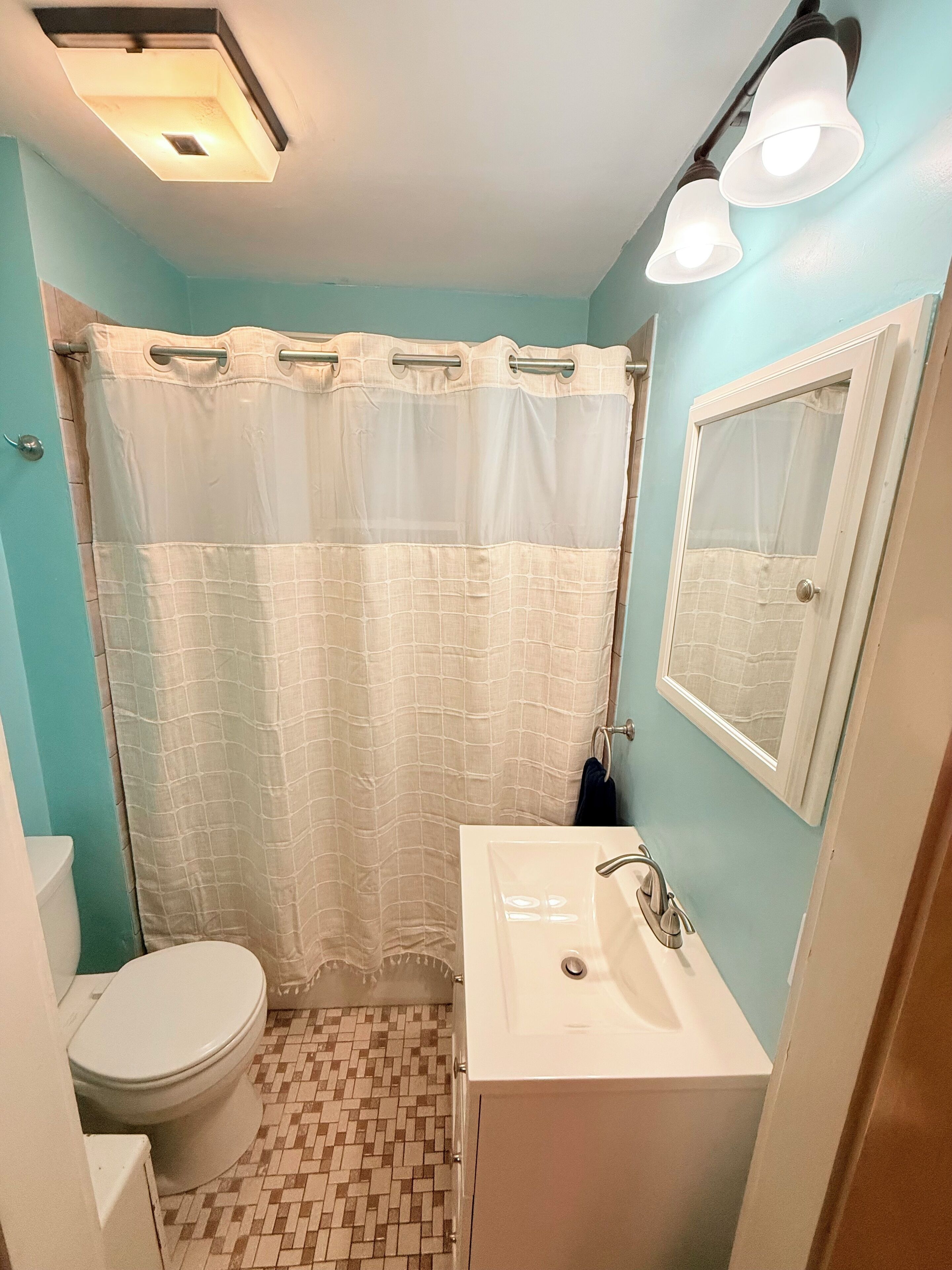 Een badkamer met toilet, wastafel en douchegordijn.