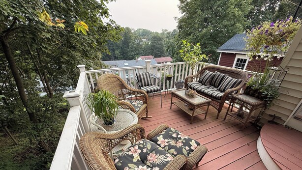 A covered patio with wicker furniture, a small table, and a potted plant. - Gallows Hill Guest House, Charming 2BR Apartment on Gallows Hill in Salem, MA (Salem)