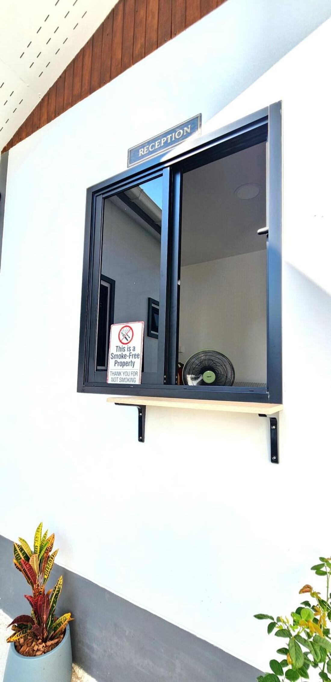 A reception window with a 'No Smoking' sign and a 'Smoke-Free Property' notice.