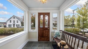 A covered porch with a wooden door, a bench, and a star-shaped light fixture.