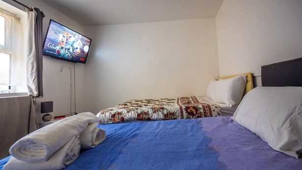 Een hotelkamer met een bed, een televisie aan de muur en een raam met gordijnen.