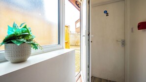 Una habitación con ventana, una puerta con número y una planta en el alféizar.