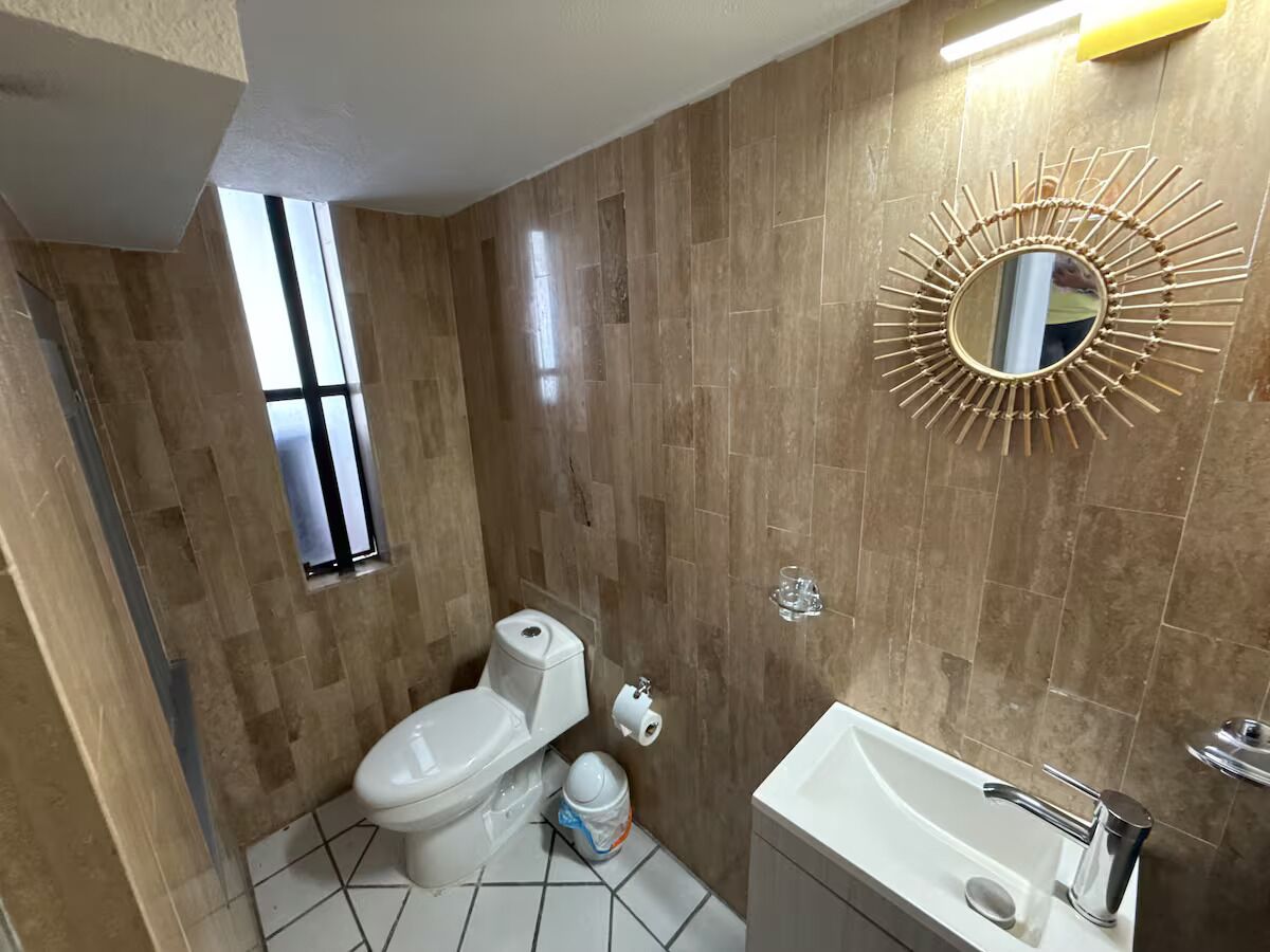 A bathroom with a toilet, sink, and mirror.