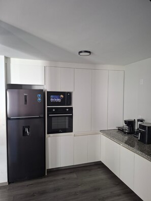 A kitchen with a refrigerator, oven, and coffee maker.