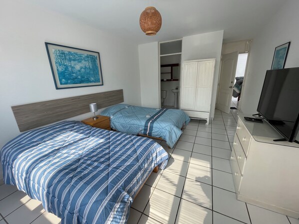 A hotel room with two beds, a TV, and a bathroom visible through an open door.