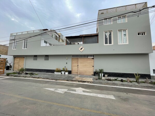 Un bâtiment moderne à deux étages, doté d’un toit plat, de grandes fenêtres et d’une entrée sécurisée par un portail.