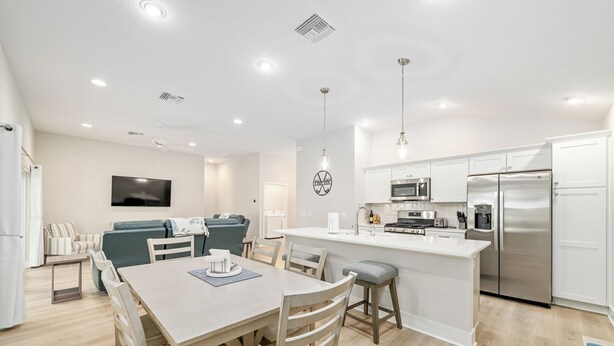 Una cocina moderna con gabinetes blancos, electrodomésticos de acero inoxidable y una isla central.
