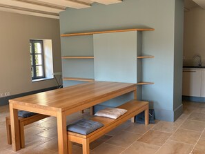 A modern kitchen with built-in shelves, a wooden table, and bench seating. - Drôme Provençale Detached house in 18th century property, tennis access (Pierrelatte)