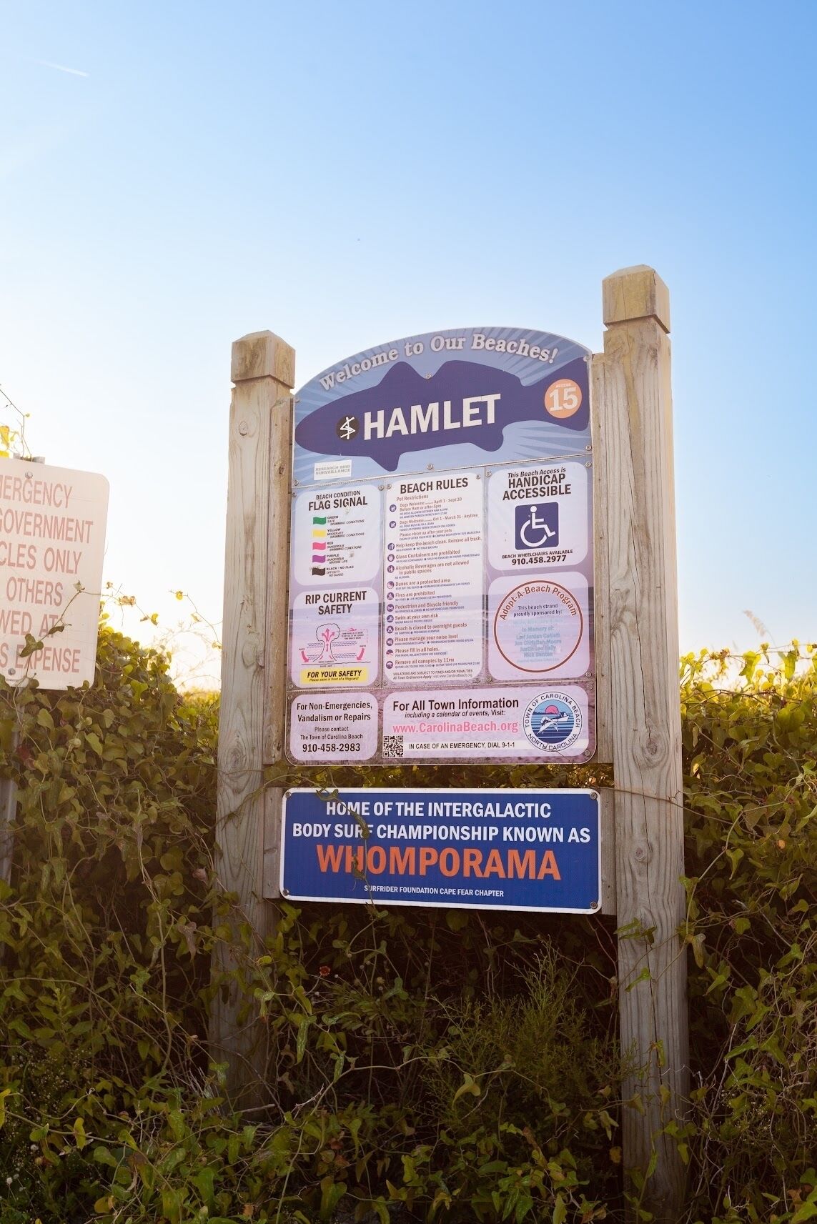 A beach sign with multiple informational panels, including beach rules, safety tips, and accessibility information.