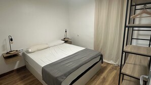 A bedroom with a bed, bedside table, hanging clothes rack, and a ceiling light. - Beautiful penthouse next to the subway enrichh lluchf (L'Hospitalet de Llobregat)