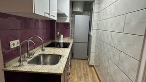 A narrow kitchen with a central island, a built-in sink, and a refrigerator. - Beautiful penthouse next to the subway enrichh lluchf (L'Hospitalet de Llobregat)