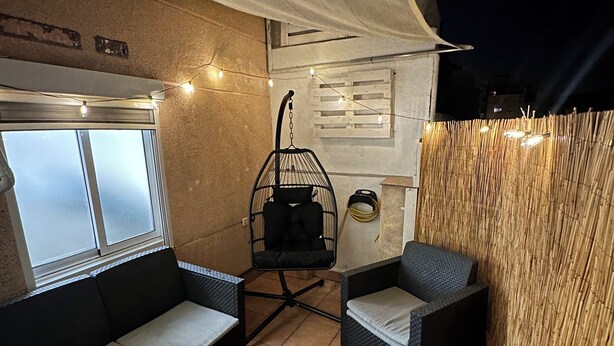 An outdoor patio with a sofa, two chairs, a small table, a hanging chair, and a bamboo fence. - Beautiful penthouse next to the subway enrichh lluchf (L'Hospitalet de Llobregat)