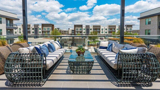 A rooftop patio with two sofas and a coffee table, surrounded by wicker furniture, under a clear blue sky. - Elegant King Bed+Stockyards+Gym+Pool+Free Parking (Fort Worth)