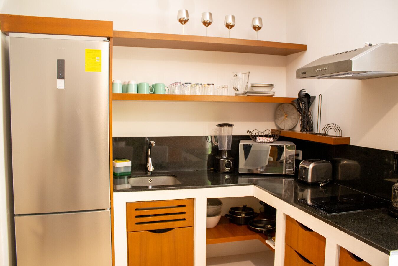 Una cocina compacta con refrigerador, pileta, microondas, tostadora y licuadora sobre la encimera.