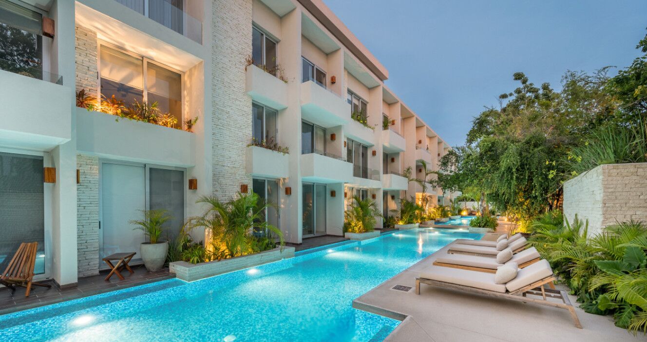 Ein modernes Hotel mit Schwimmbad, Außenbereich und üppiger Bepflanzung.