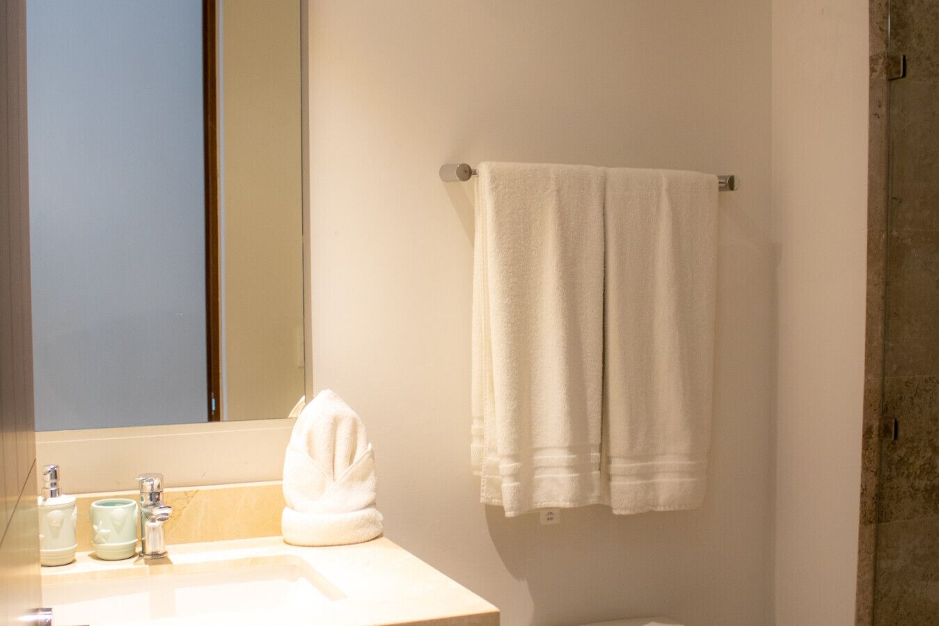 Une salle de bain avec un lavabo blanc, un miroir et une serviette suspendue à un porte-serviettes en métal.