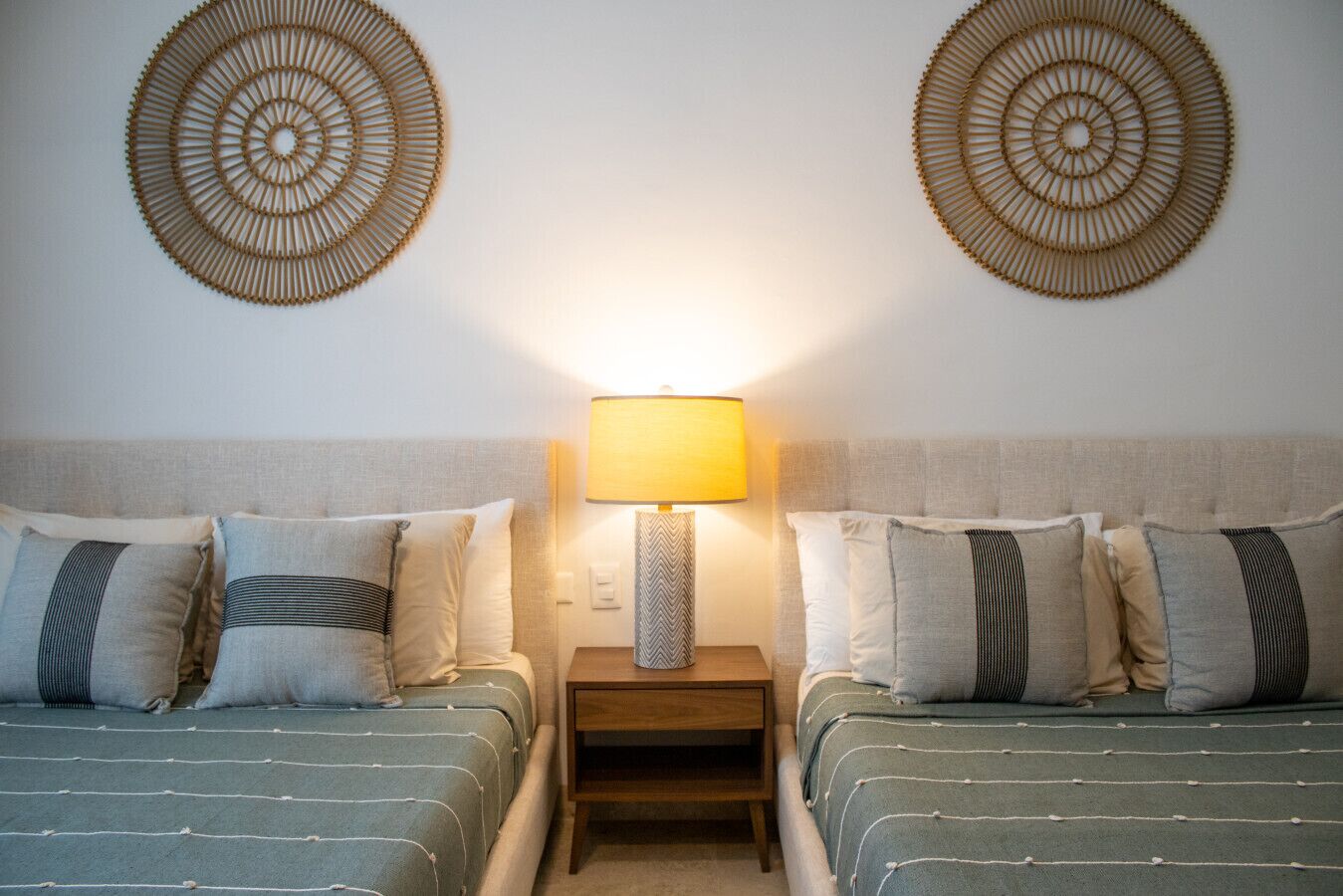 Une chambre d’hôtel avec deux lits, une table de chevet avec une lampe et deux éléments de décoration murale.