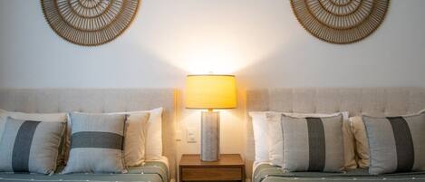 Une chambre d’hôtel avec deux lits, une table de chevet avec une lampe et deux éléments de décoration murale.