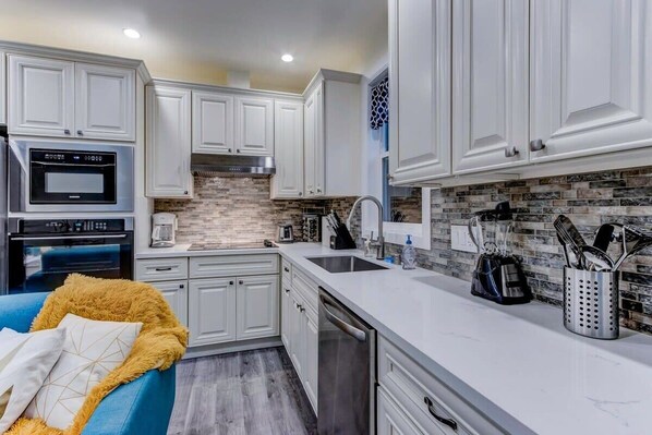A modern kitchen with white cabinets, a built-in oven, and a stone backsplash. - @ Marbella Lane - Bright and Cozy Home Near SFO (San Mateo)