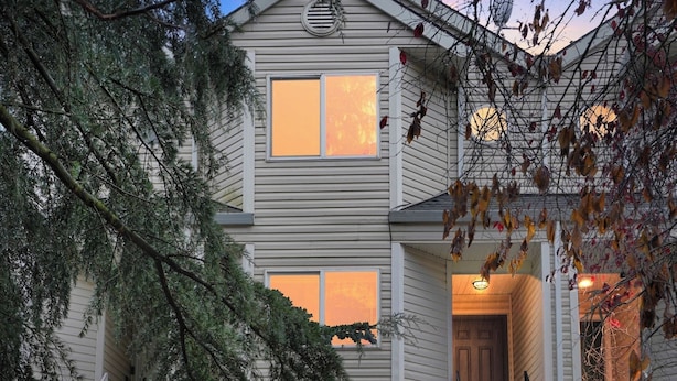Ein zweistöckiges Haus mit Garage, einer Veranda und einer Treppe zum Obergeschoss.