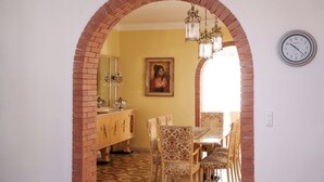 A dining area with a brick archway, patterned chairs, a table, and a chandelier. - VILLA VENERA - Amazing Holiday House (Solarino)