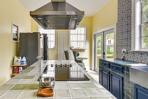 Uma cozinha com ilha central, eletrodomésticos de aço inoxidável e uma janela grande.