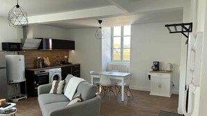 A compact living space with a kitchenette, a dining area, and a seating area with a sofa and a coffee table. - Modern apartment in the heart of the Auvergne. 10 min from Les Termes de Châtel-Guyon. (Combronde)