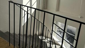 A staircase with black railings leading to a landing. - Modern apartment in the heart of the Auvergne. 10 min from Les Termes de Châtel-Guyon. (Combronde)