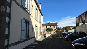 A narrow street with buildings on either side, a gravel path, and parked cars. - Modern apartment in the heart of the Auvergne. 10 min from Les Termes de Châtel-Guyon. (Combronde)