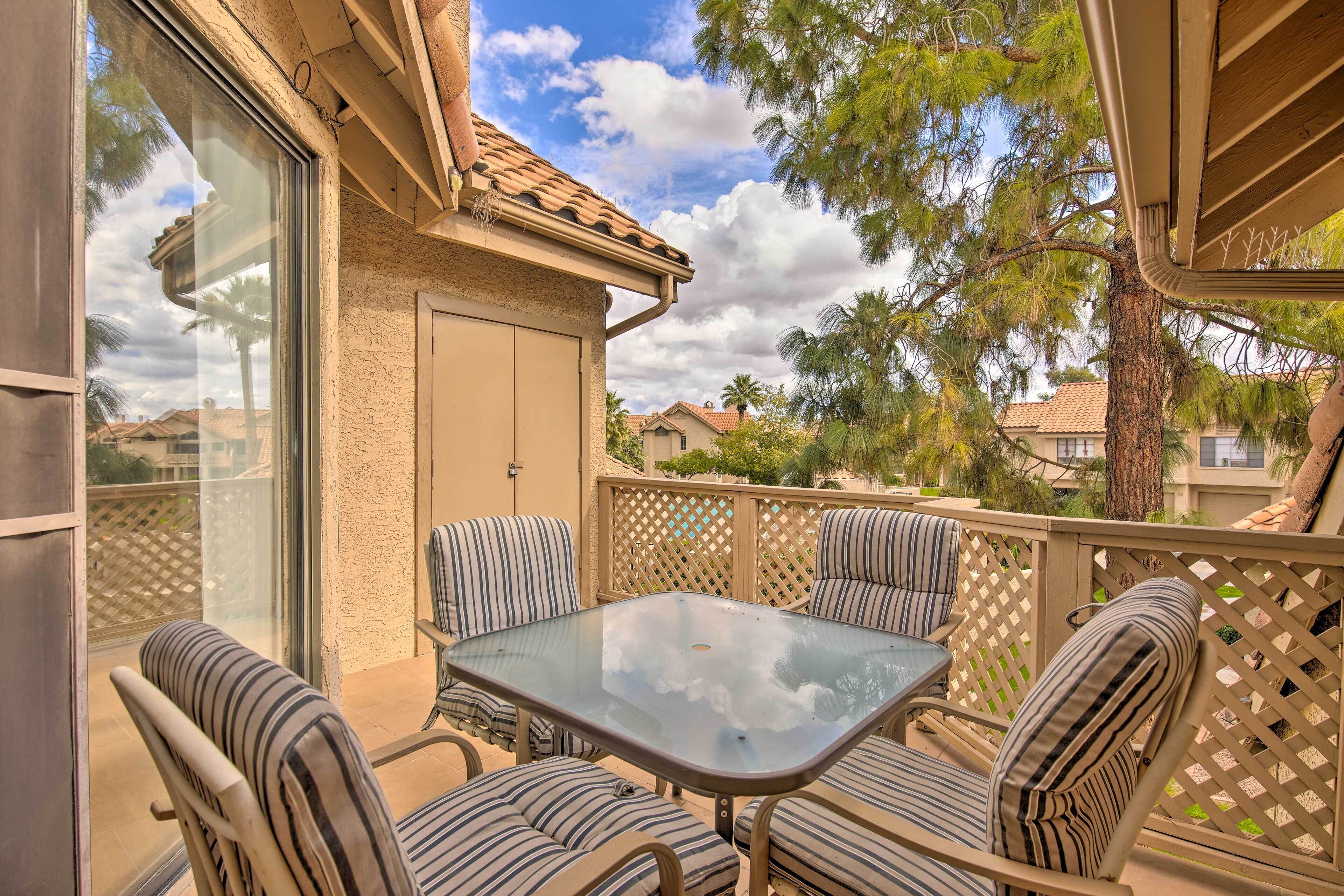 A covered outdoor patio with a glass table and striped cushioned chairs.