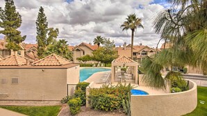 Zona residencial con piscina, palmeras y casas con techos de tejas rojas.