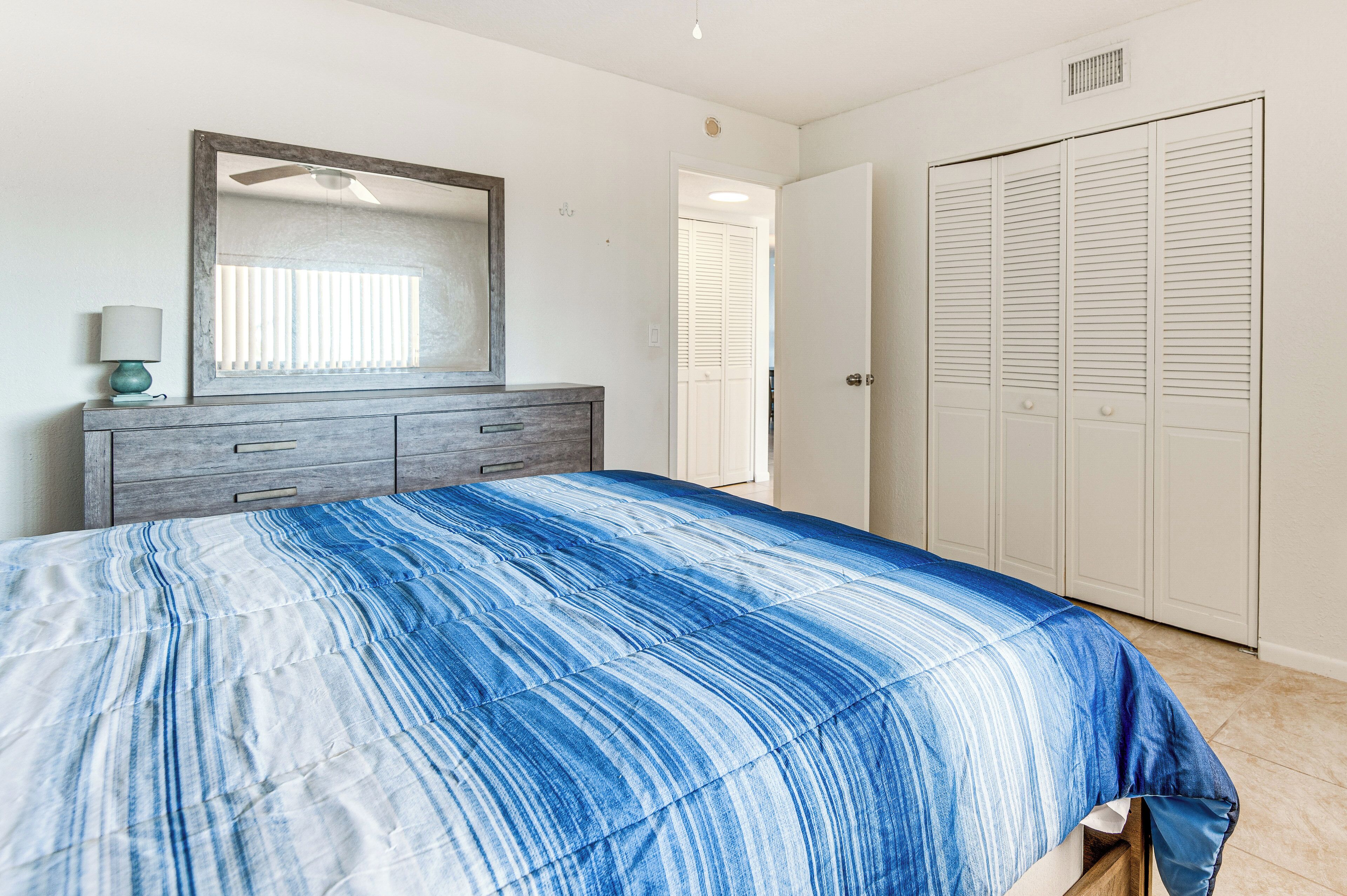A bedroom with a bed, a dresser, a mirror, and a closet.