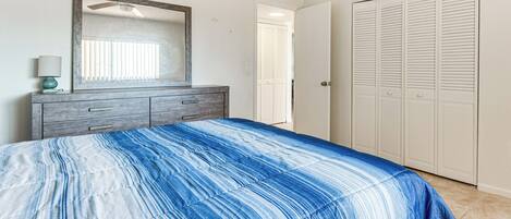 A bedroom with a bed, a dresser, a mirror, and a closet.