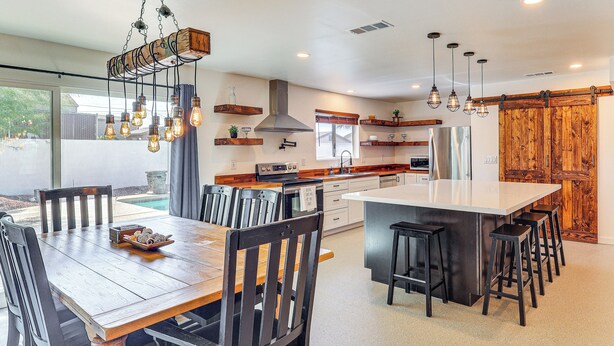 Una cocina moderna con una isla central, taburetes de bar e iluminación colgante.