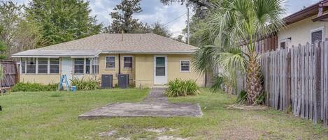 A single-story house with a front yard, a wooden fence, and a palm tree.