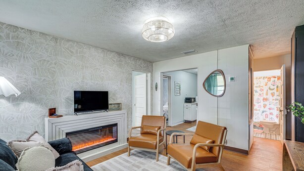 A modern living room with a fireplace, leather chairs, a flat-screen TV, and a patterned wall. - Little Cove Cottage! Walk to Dtwn Panama City (Panama City)