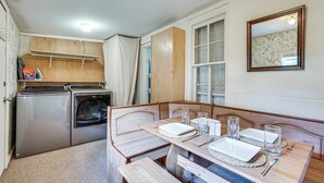 A compact kitchen with a washing machine, a small dining table with benches, and a mirror on the wall. - Little Cove Cottage! Walk to Dtwn Panama City (Panama City)
