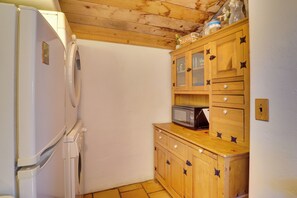 Una cucina compatta con un frigorifero bianco, un forno a microonde e pensili in legno decorati con motivi a farfalla.