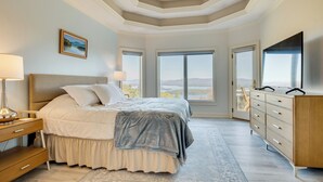 Ein Schlafzimmer mit einem großen Bett, einem Schminktisch, einem Fernseher und Blick ins Freie.