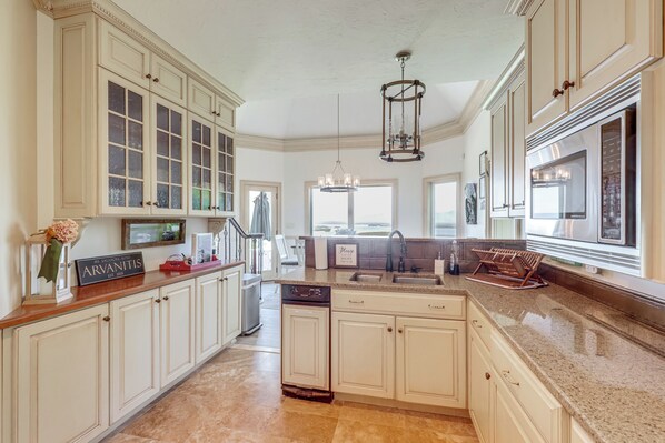 A kitchen with white cabinetry, a granite countertop, a built-in oven, and a chandelier.