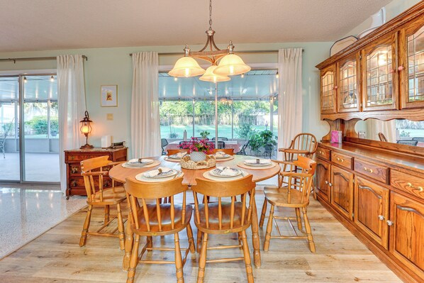 Un coin repas avec une table et des chaises en bois, un lustre et une cuisine dotée de meubles de rangement en bois.
