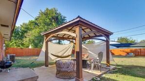 A covered patio area with a wooden pergola, a hammock, and a table with chairs. - Easy OKC Access! Quiet Home w/ Yard & Workspace (Midwest City)