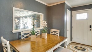 A dining area with a wooden table, white chairs, and potted plants. - Easy OKC Access! Quiet Home w/ Yard & Workspace (Midwest City)