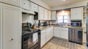 A kitchen with white cabinets, a stove, a microwave, and a dishwasher. - Easy OKC Access! Quiet Home w/ Yard & Workspace (Midwest City)