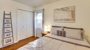 A bedroom with a bed, a ladder with pictures, a door, and a window with curtains. - Easy OKC Access! Quiet Home w/ Yard & Workspace (Midwest City)